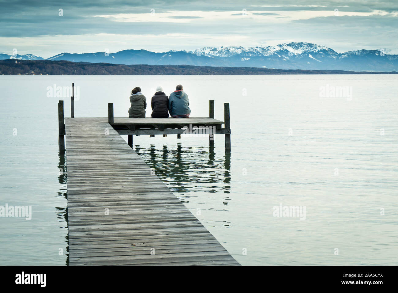 Drei Menschen auf einem Steg am Starnberger See, Deutschland im inverno Foto Stock