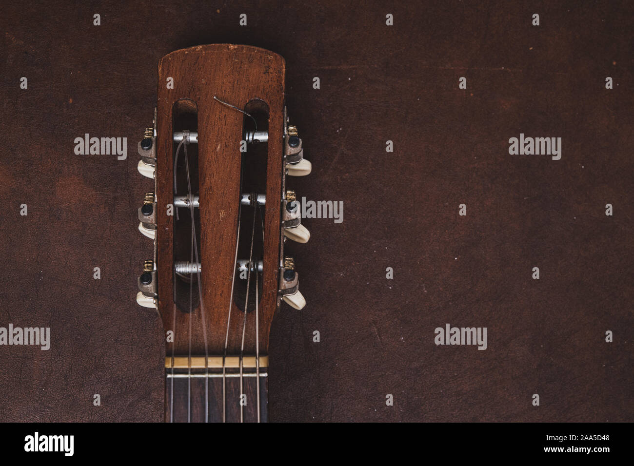 Elevato angolo di visione vintage vecchia chitarra acustica di testa e piroli dettagli su sfondo di legno Foto Stock