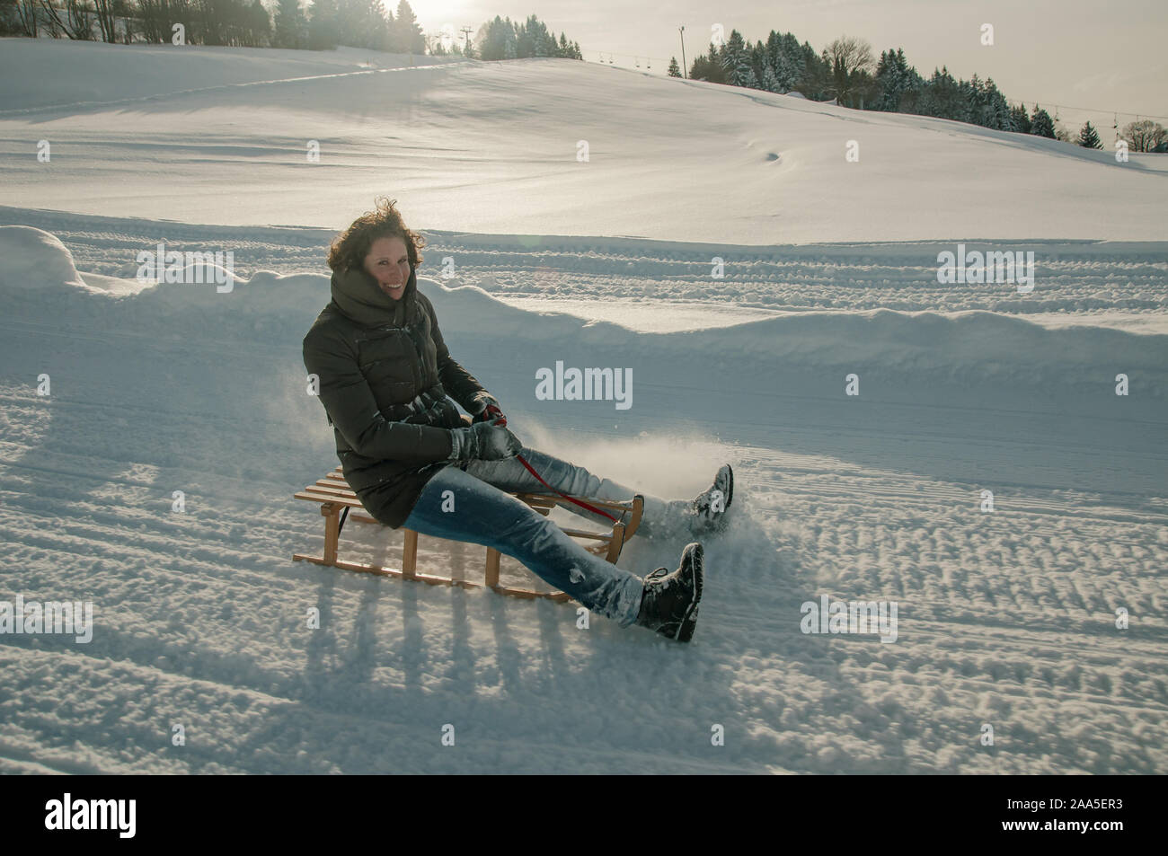 Giovane donna avendo divertimento sulla slitta nella neve Foto Stock