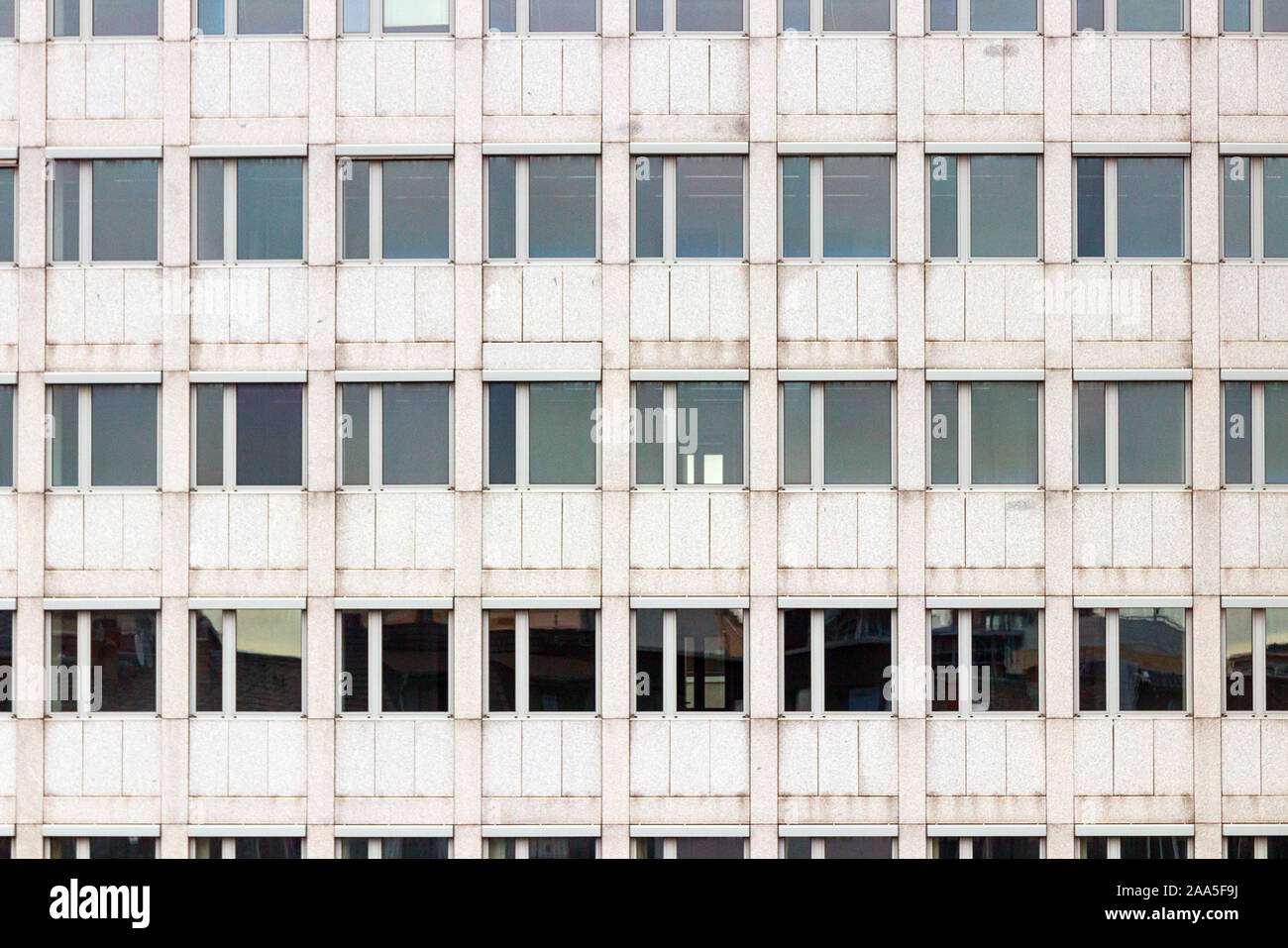 La facciata di colore grigio di un multipiano edificio per uffici con uno schema simmetrico di windows. Foto Stock