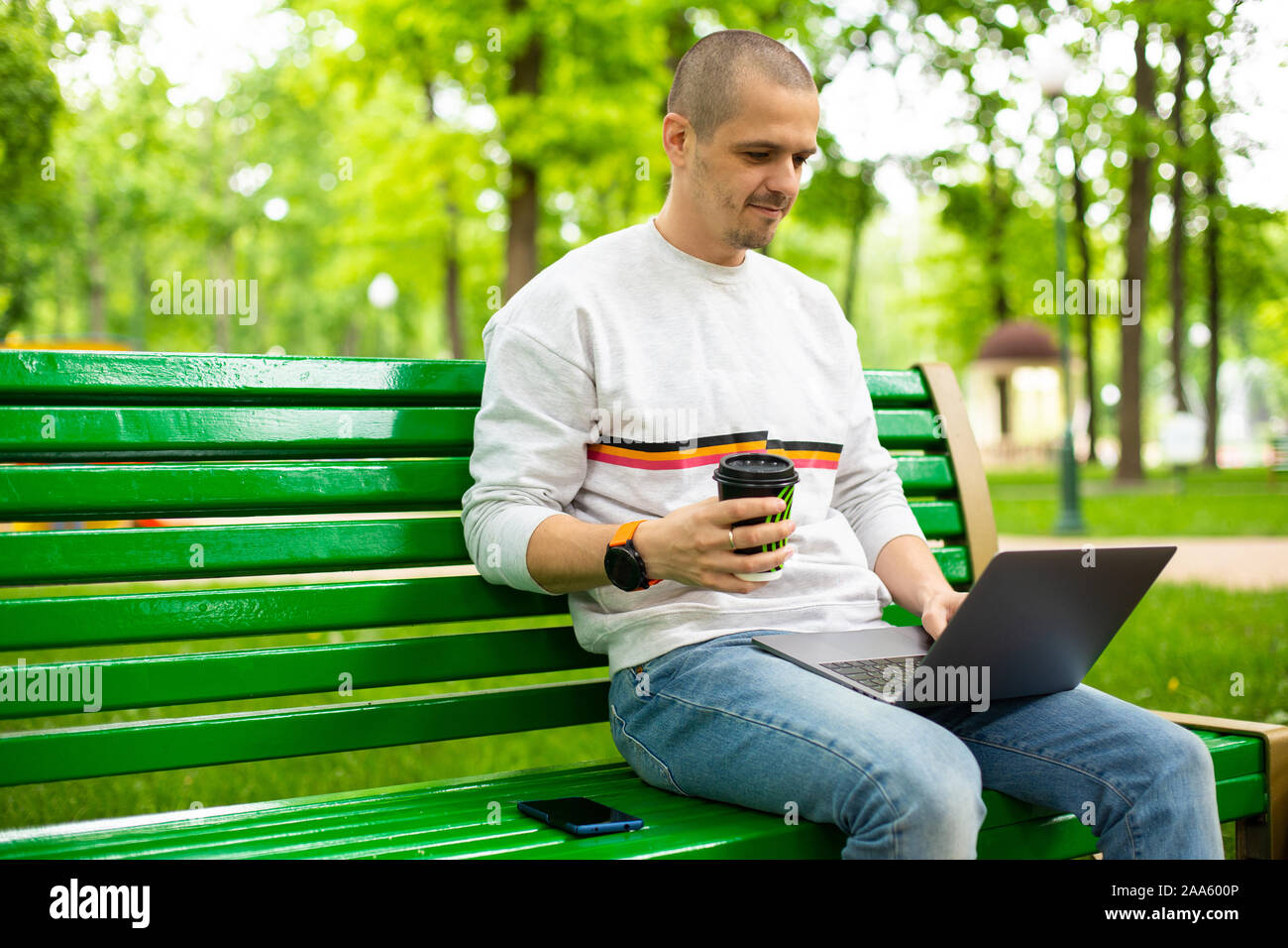 Uomo con tazza di caffè e di lavoro sul computer portatile Foto Stock