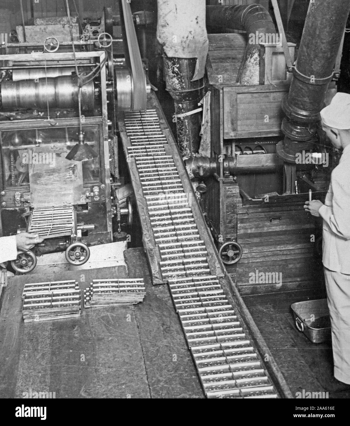 Industrie di guerra - Candy - INDUSTRIE DELLA GUERRA. Rimozione di barrette di cioccolato dalla sagomatura padelle. Tavolette di cioccolato sono riportati i nostri soldati nella parte anteriore come una parte regolare della loro razioni di campo ca. 1918 Foto Stock