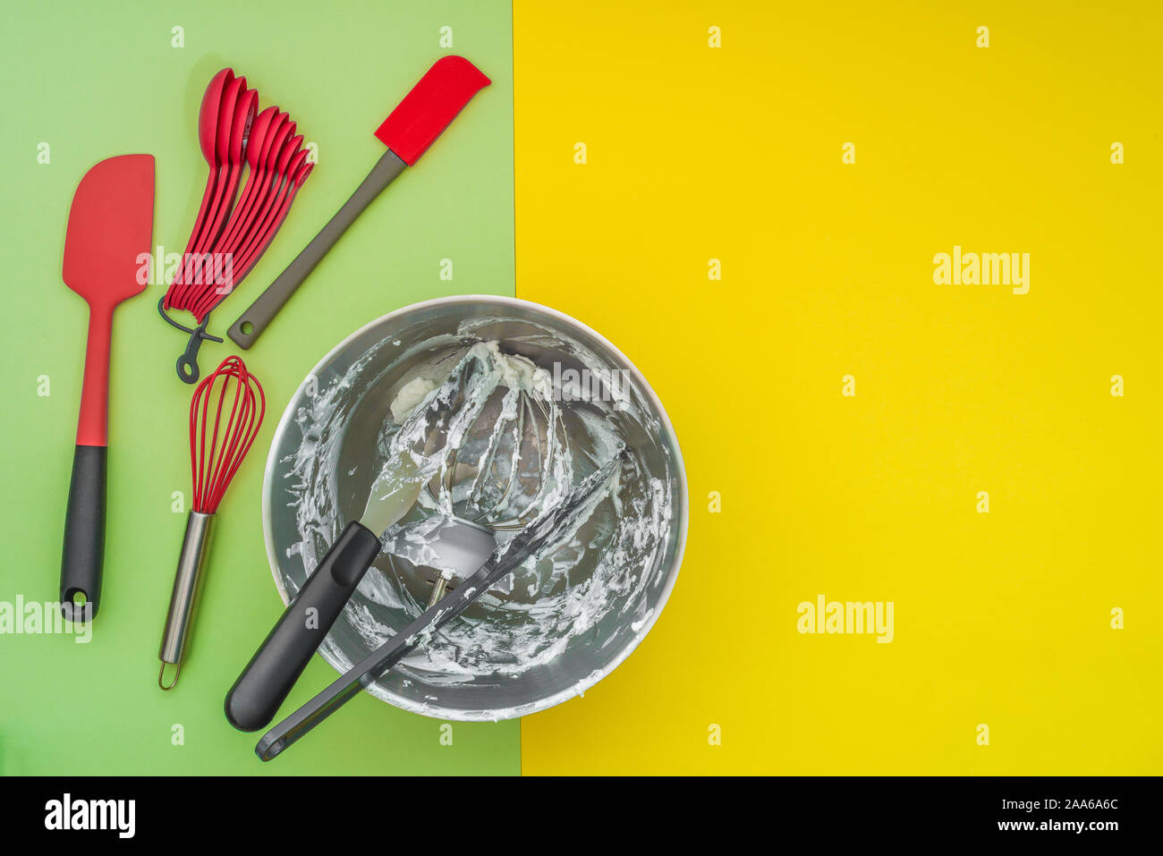 Utensili da forno accessori, e la vaschetta di miscelazione sul piatto lay, verde sfondo giallo Foto Stock