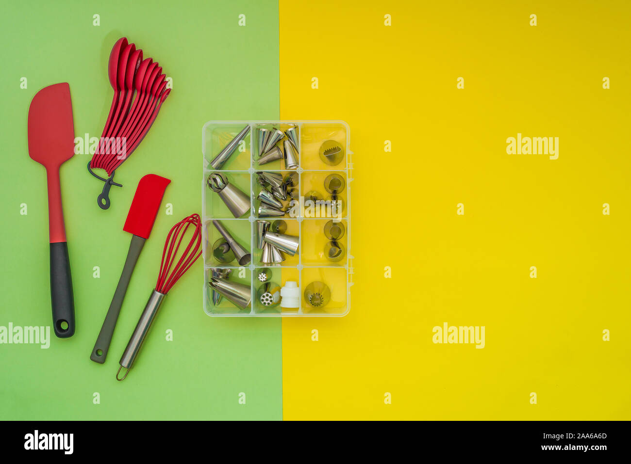 Utensili da forno e una scatola di tubazioni ugelli sul piatto lay, verde sfondo giallo Foto Stock