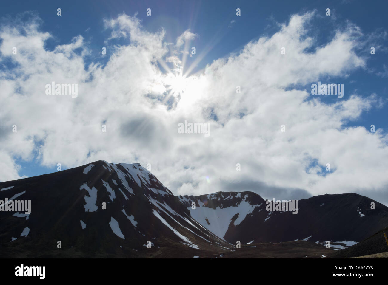 Un brillante sunburst su innevate montagne islandese. Foto Stock