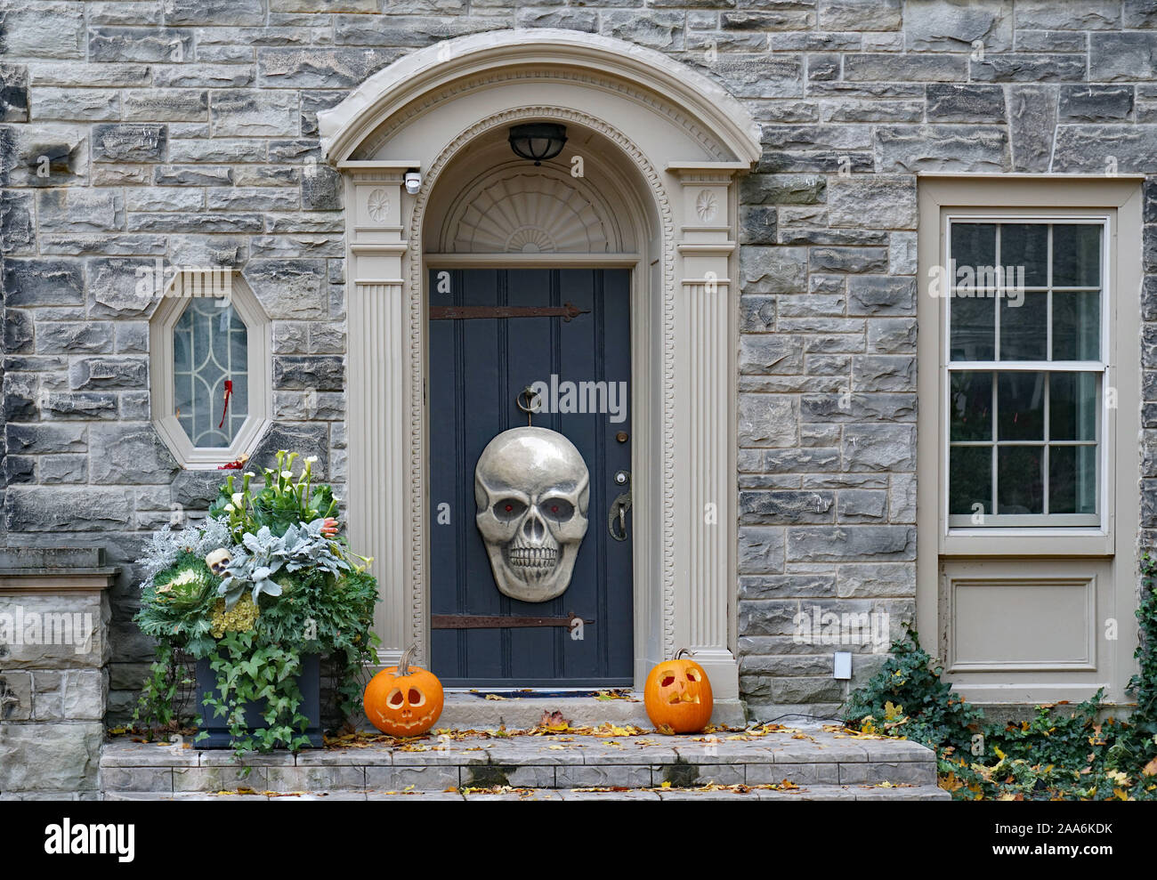 La parte anteriore della casa in pietra con cranio e zucche di Halloween decorazioni Foto Stock