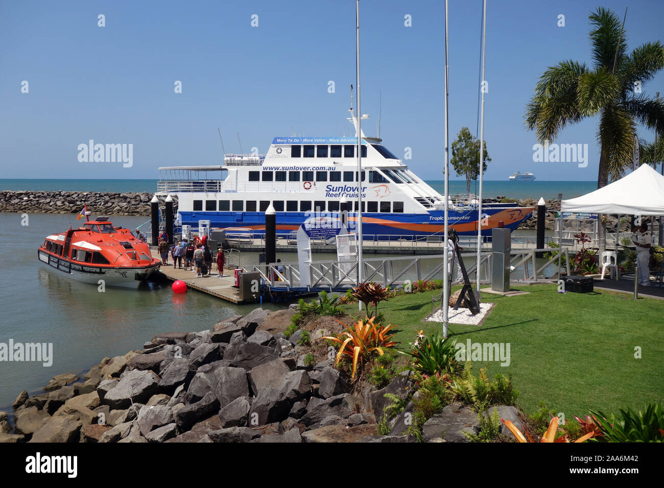 I passeggeri delle navi da crociera Pacific Dawn (visibile sull'orizzonte) trasferimento al reef locale tour in barca, Yorkey manopola della Marina, Cairns, Queensland, Australi Foto Stock