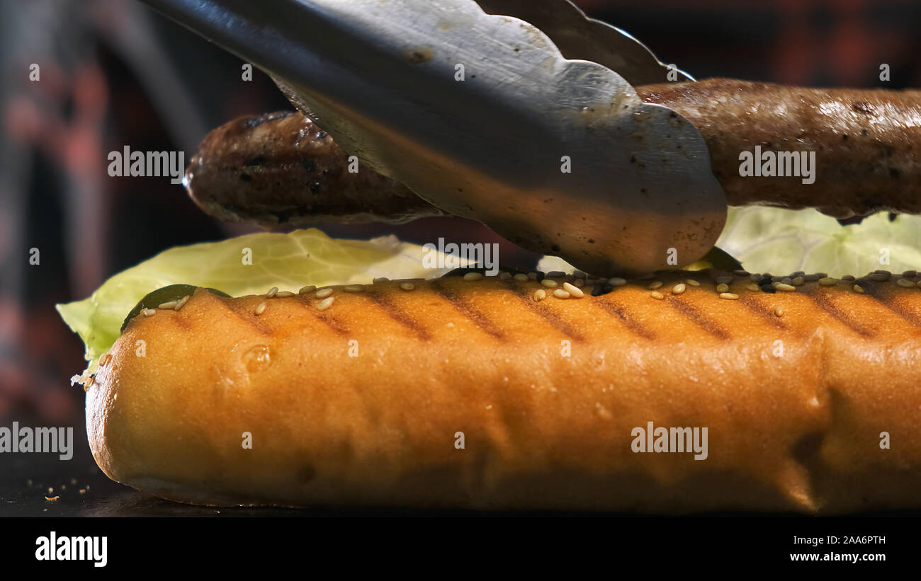 Extra di close-up di cuocere le mani preparare un hot dog, egli mette salsicce di manzo Foto Stock