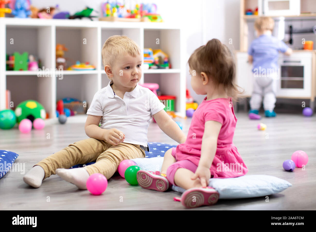 Bambini che giocano con i giocattoli colorati. Capretto piccolo ragazza e toddler boy in asilo nido. I bambini giocano a cura di giorno o di età prescolare. Foto Stock