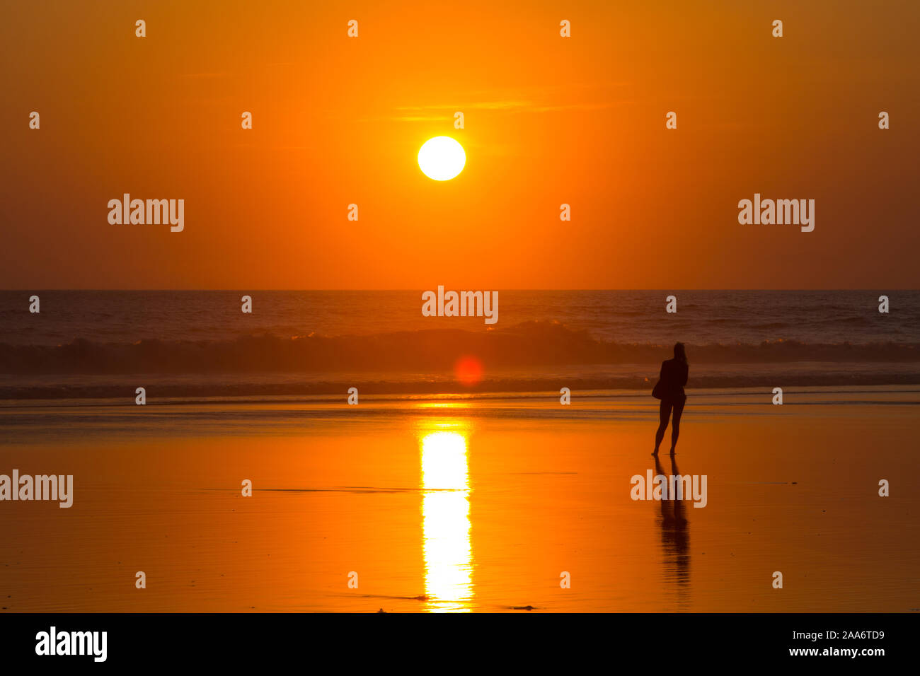 Vista posteriore di una donna che guarda la splendida scena del tramonto a Kuta Beach, Bali. Indonesia. Foto Stock