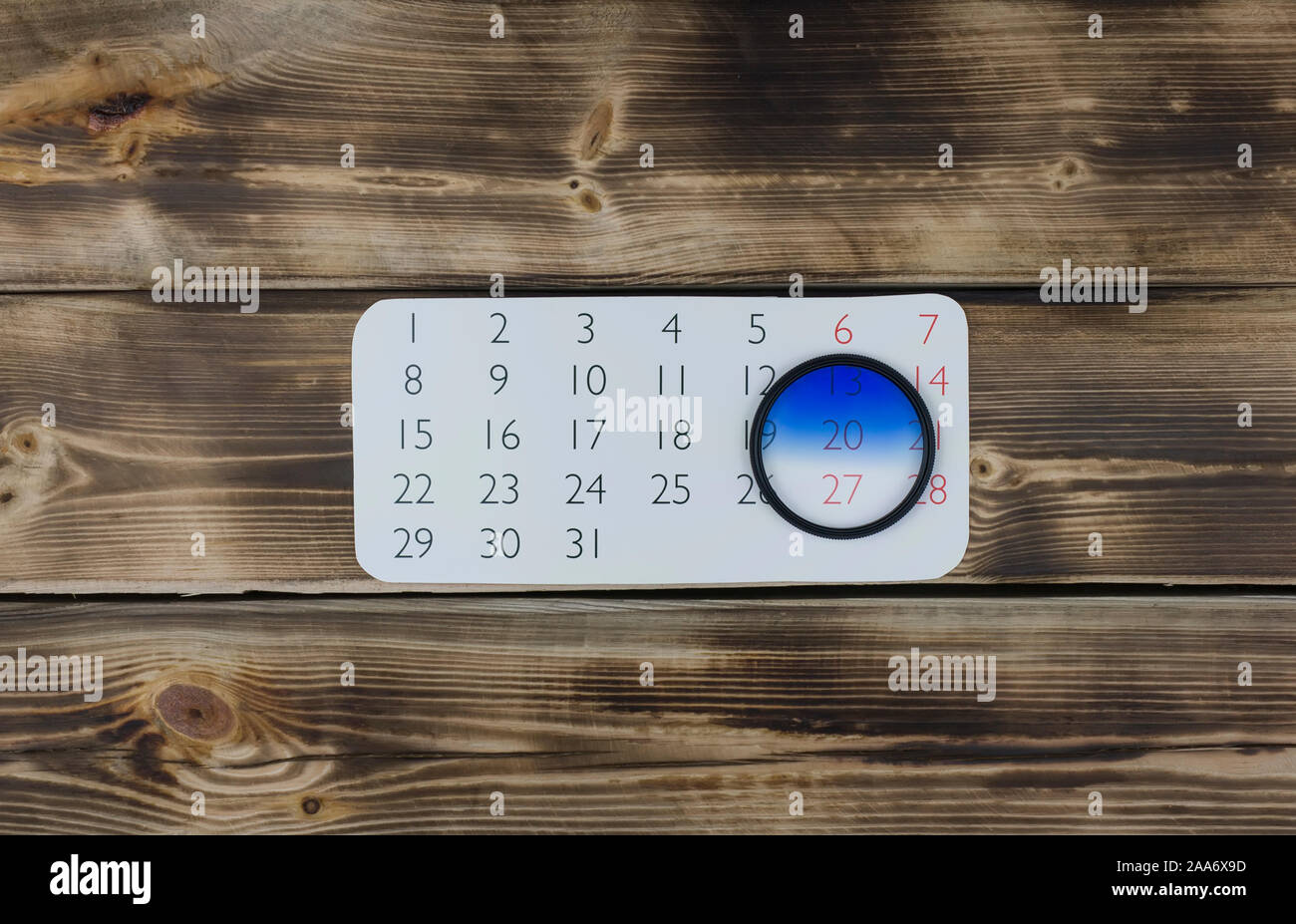 Foglio di calendario e la lente della fotocamera il filtro su legno Foto Stock