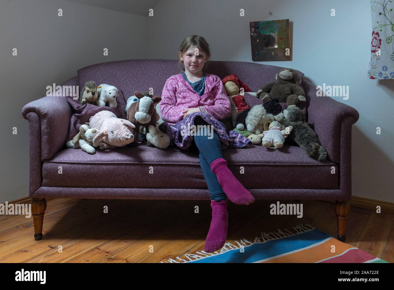 Ragazza 6 anni seduto sul divano con il suo animali imbalsamati, Meclemburgo-Pomerania, Germania Foto Stock