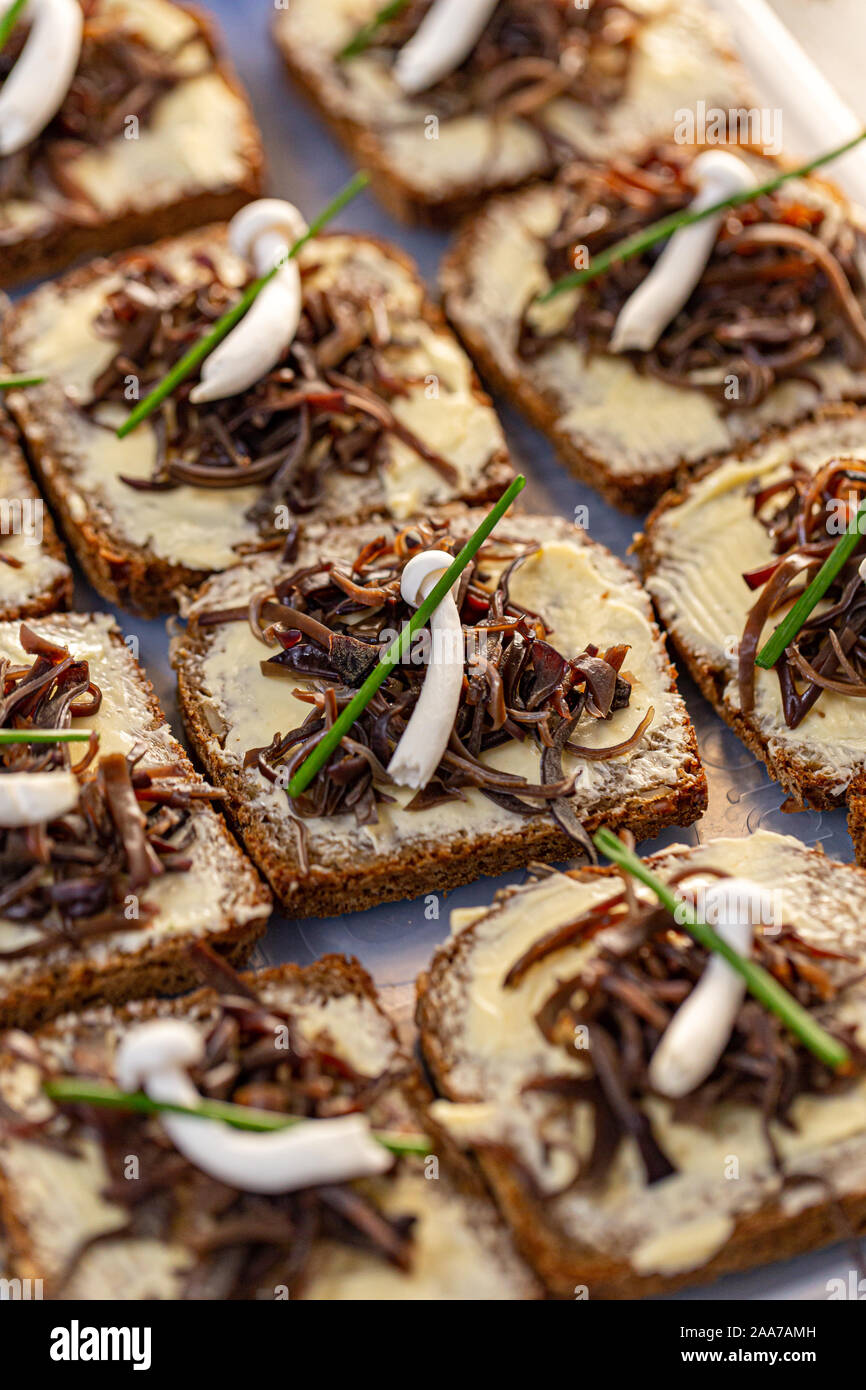 Fette di pane fresco con burro decorate con legno marinato orecchio commestibili e di funghi shimeji Foto Stock