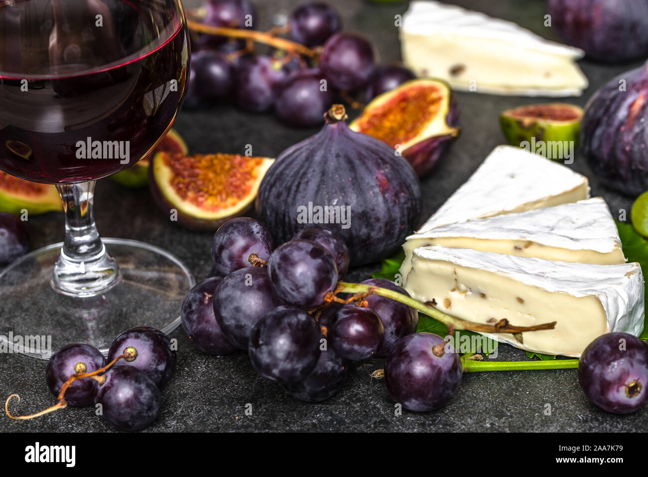 Vino e degustazione di formaggi. Bicchiere di vino rosso e cibo, formaggio francese, fichi e uva. Foto Stock