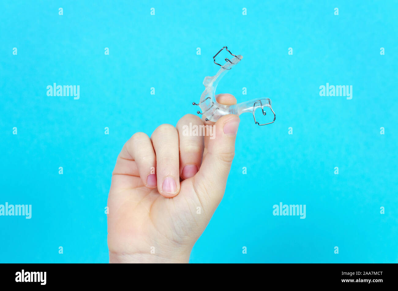 Bambino la mano con apparecchio ortodontico su sfondo blu Foto Stock