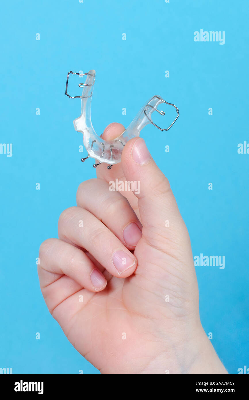 Bambino la mano con apparecchio ortodontico su sfondo blu Foto Stock