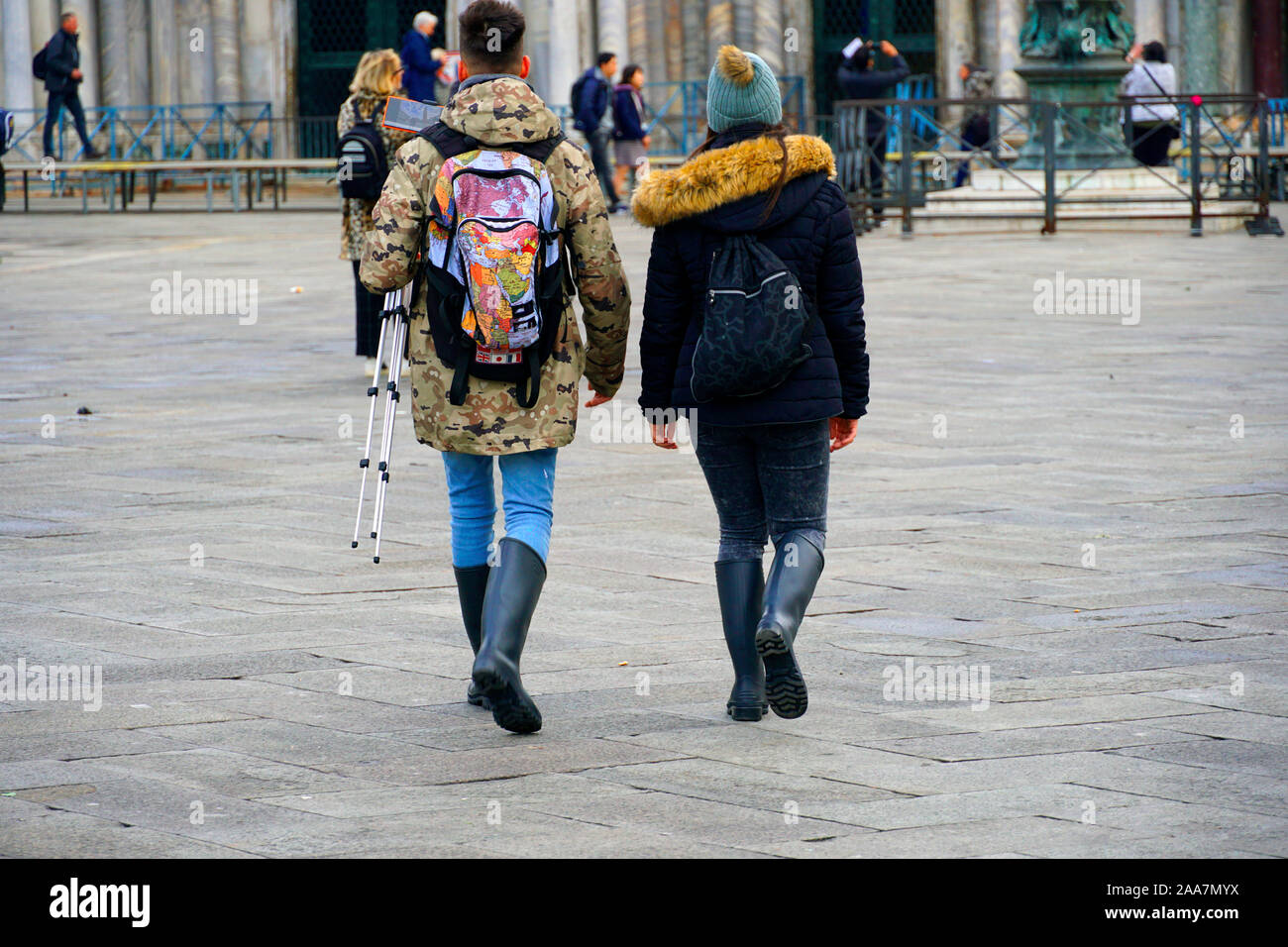 Due giovani turisti a piedi su piazza San Marco in stivali di gomma due giorni dopo il diluvio a Venezia, Italia il 18 novembre 2019 Foto Stock