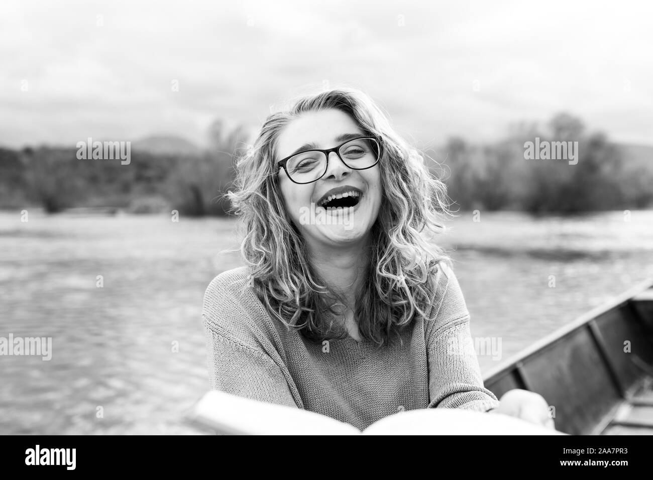 Ritratto di giovane bella donna seduta su una barca e la lettura di un libro. È bookworm e sceglie fra pochi libri. Foto Stock