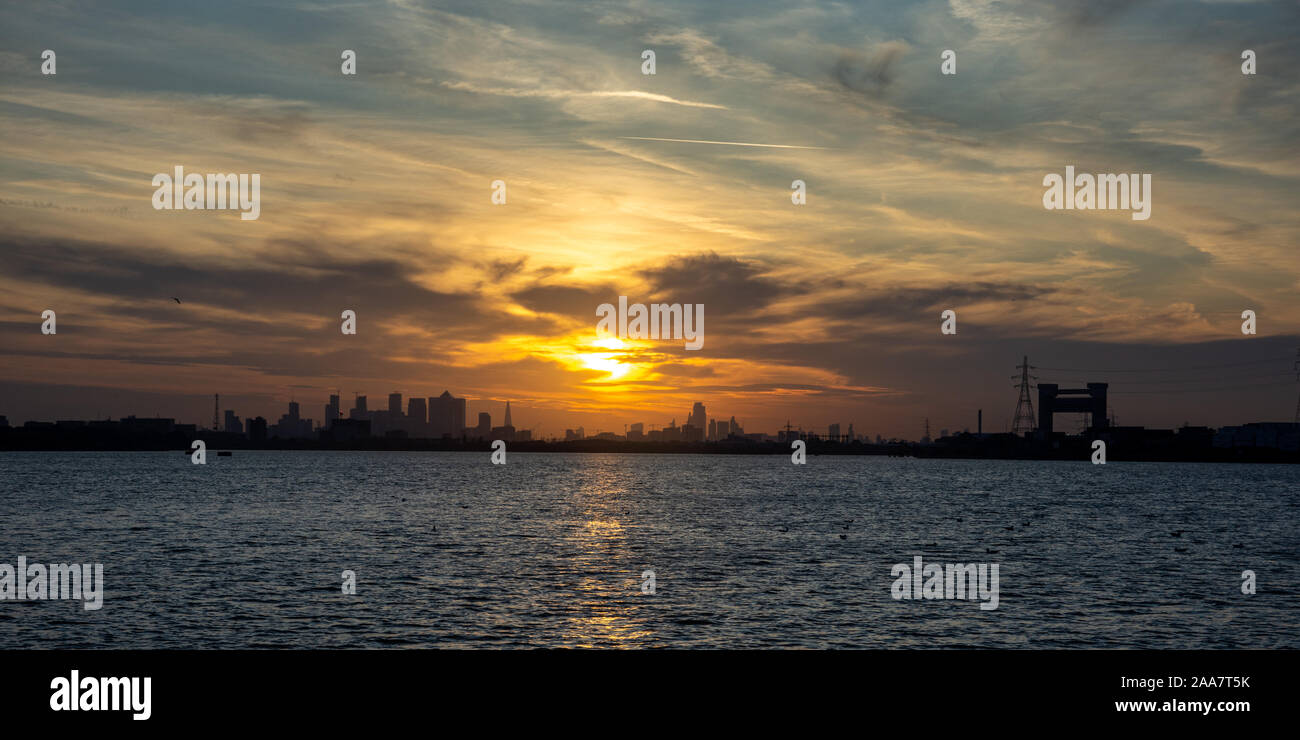 Il dall'alto della City of London Docklands e Canary Wharf quartieri degli affari si stagliano contro il sole di setting come vista dal fiume Tham Foto Stock