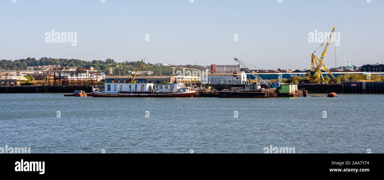 Rochester, England, Regno Unito - 21 Settembre 2019: magazzini abbandonati e gru stand in post-industrial wasteground accanto al fiume Medway in Rochester. Foto Stock