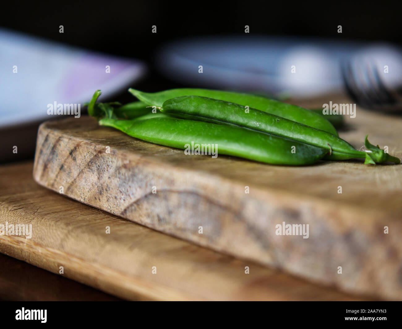 Piselli verdi su un tagliere di legno Foto Stock
