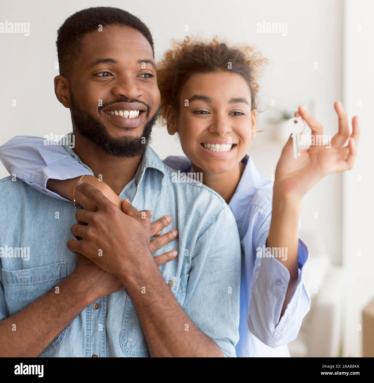 Felice coppia nero avvolgente che mostra permanente della chiave nella nuova casa Foto Stock