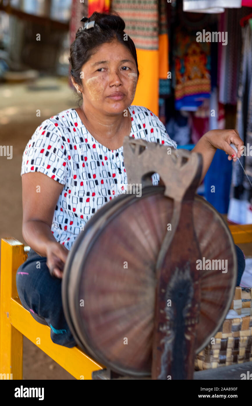 I vecchi femmina birmano weaver utilizza una rotella di filatura per creare il thread per la tessitura di tessuti tradizionali di Bagan (pagano) regione del Myanmar (Birmania) Foto Stock