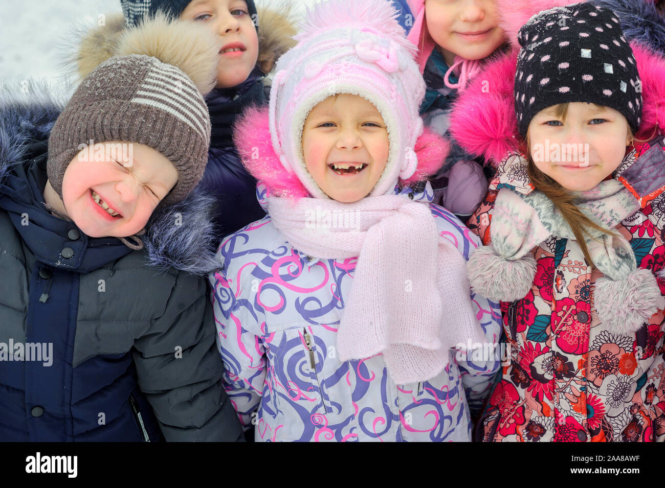 Un gruppo di bambini stanno giocando e divertendosi su un parco giochi invernale. Amici stanno abbracciando e sorridente. Divertimento invernale. vacanze Foto Stock