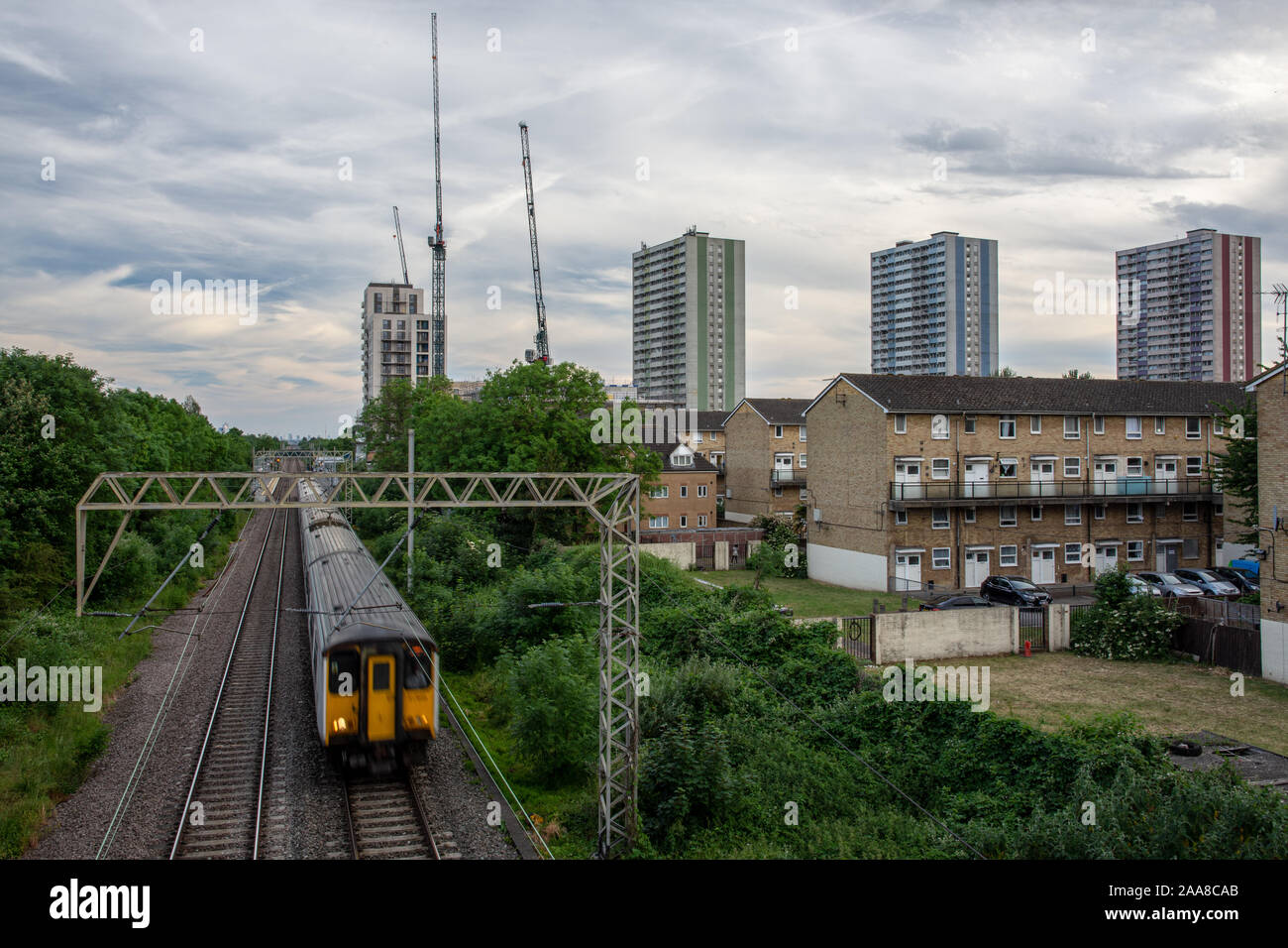 London, England, Regno Unito - 1 Giugno 2019: una maggiore Anglia commuter train passa consiglio alloggiamento del Alma Station Wagon a meditare la fine nel nord di Londra subu Foto Stock