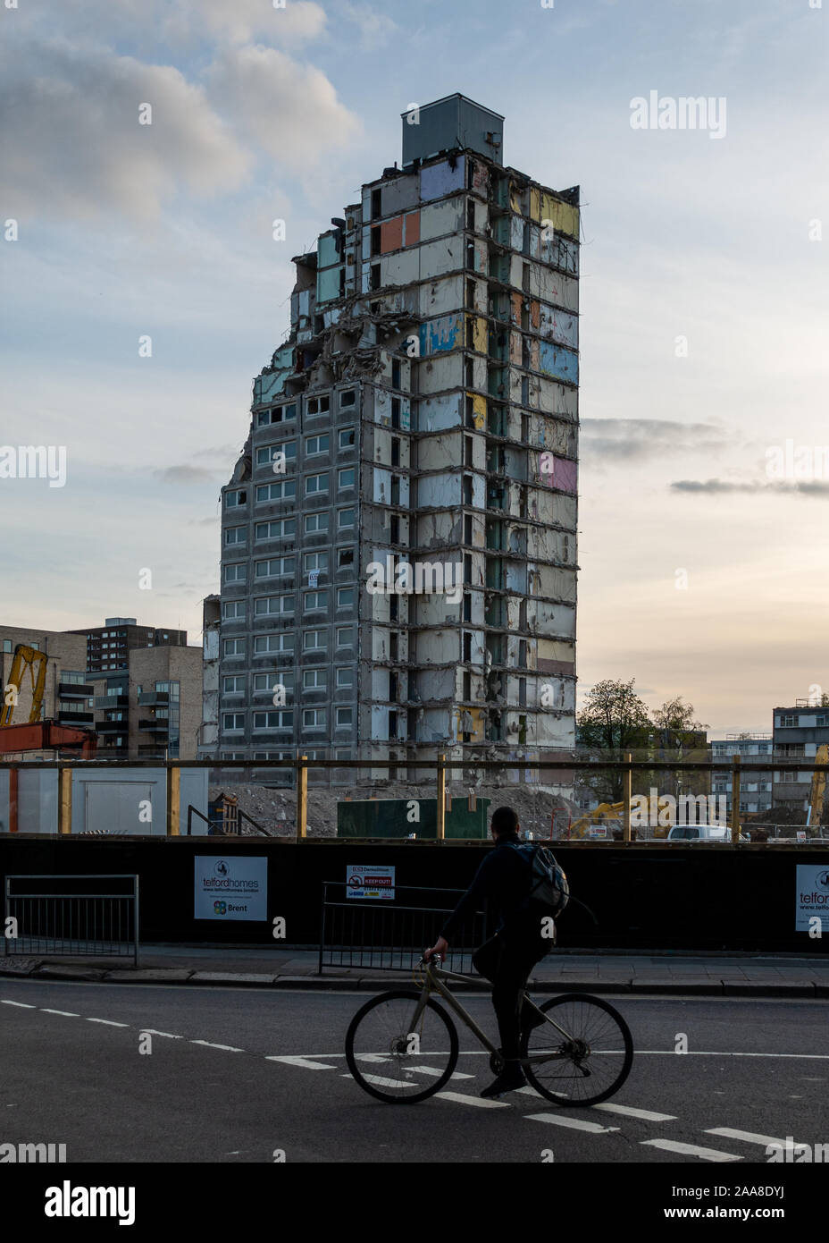 London, England, Regno Unito - 16 Aprile 2018: Un ciclista guarda alla demolizione di un alto consiglio alloggiamento blocco a torre a sud Kilburn Estate in t Foto Stock