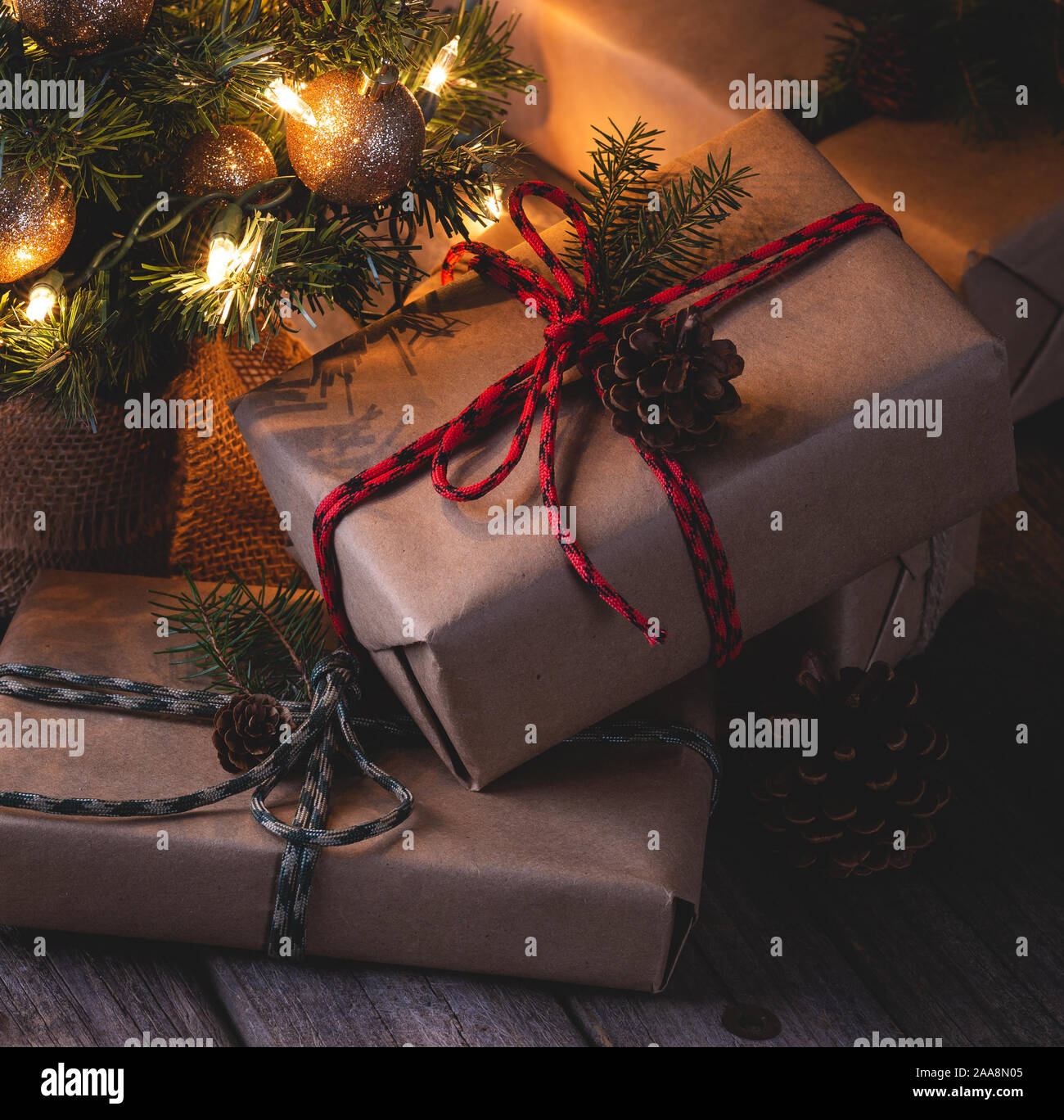 Scena notturna del Natale regali avvolti in carta marrone e legati con spago con decorate albero in background Foto Stock