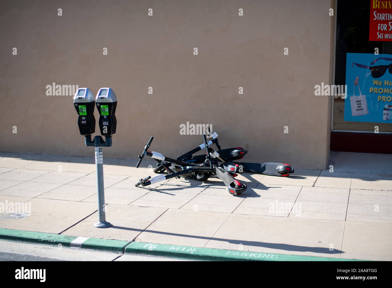 Più scooter elettrici sparsi sul terreno di un marciapiede Foto Stock