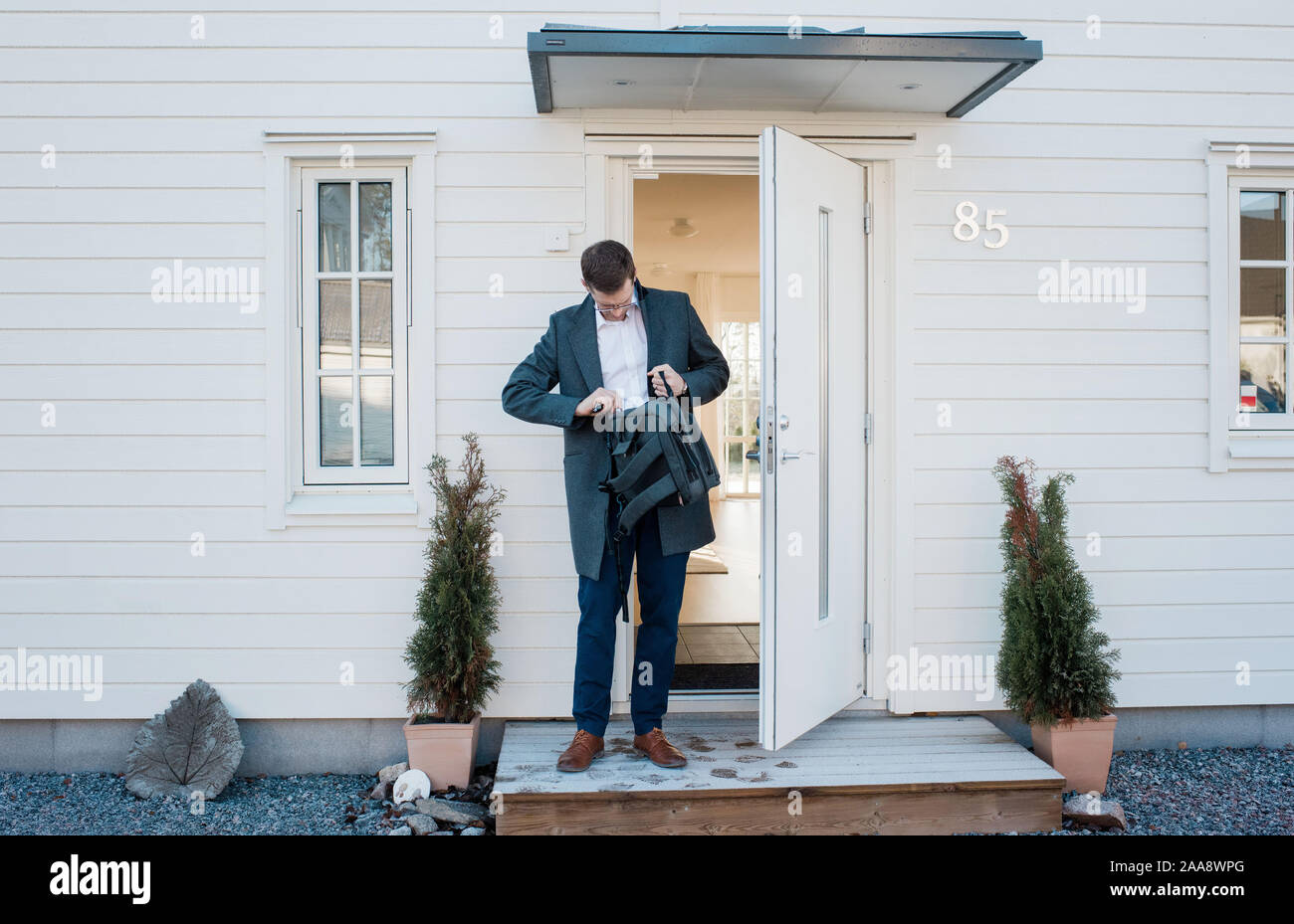 Uomo di uscire di casa per lavorare cercando nella sua borsa per bloccare la porta Foto Stock