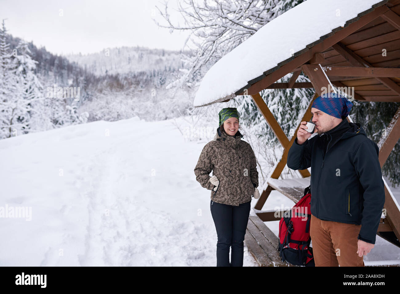 Sorridente coppia giovane di bere il caffè durante una escursione invernale Foto Stock