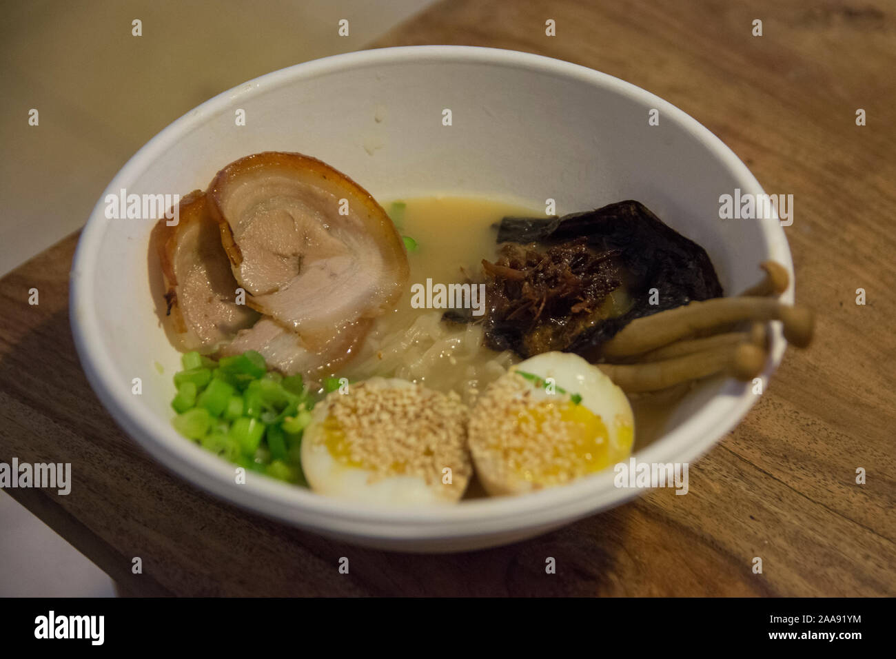 Una ciotola di tradizionale giapponese Ramen di maiale minestra con funghi Enoki, medio-uova sode, scalogno, alghe e carne di maiale Foto Stock