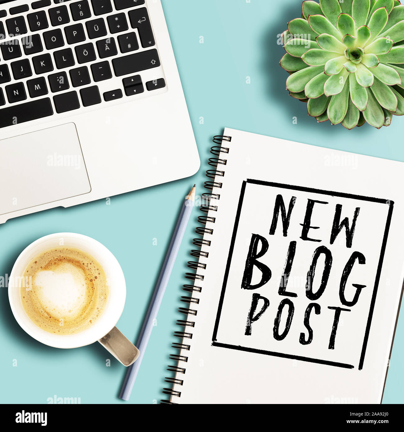Vista dall'alto di parole New blog post scritti sul blocco note a spirale sulla scrivania con computer portatile e pianta in vaso Foto Stock