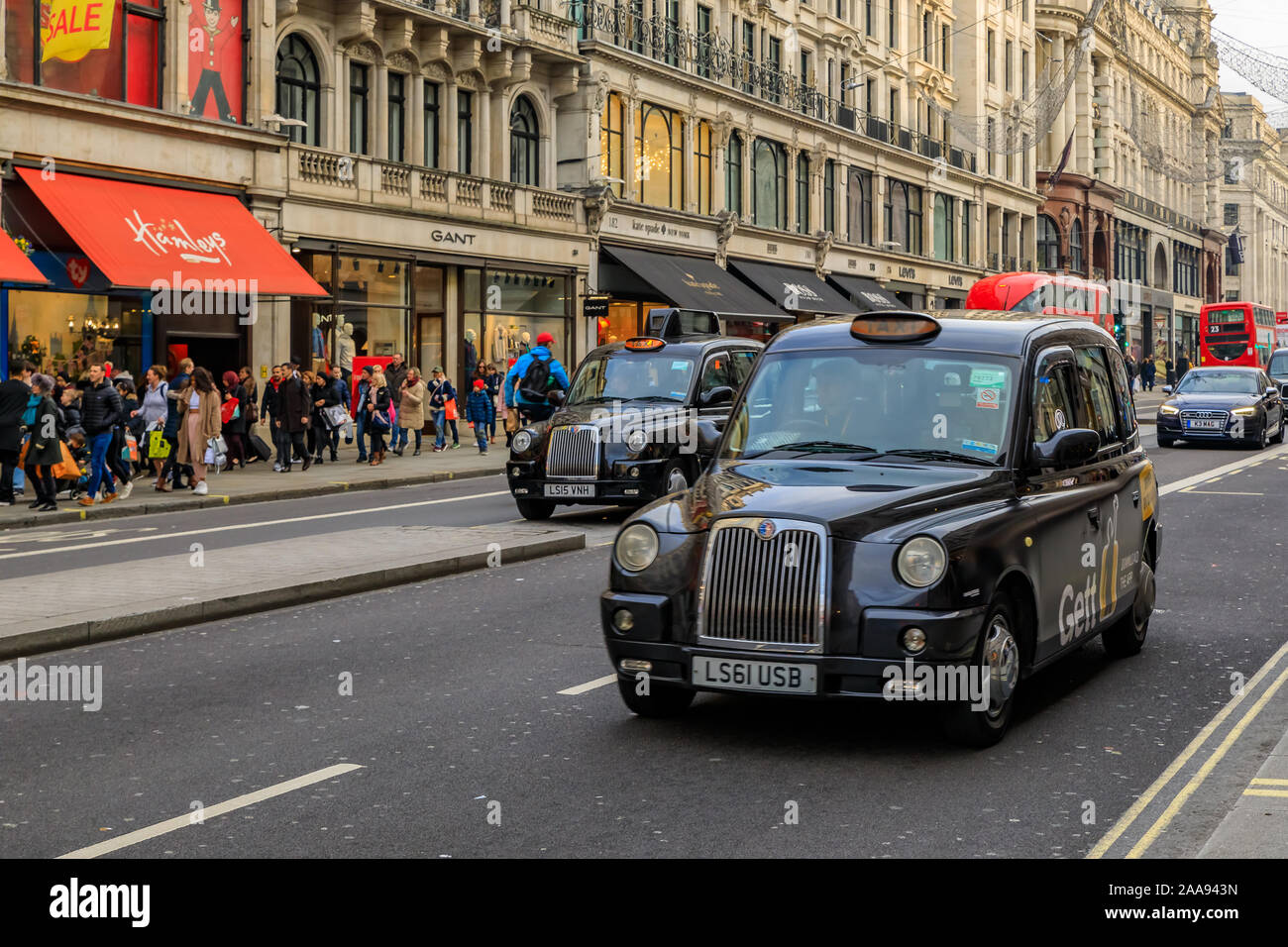 London, Regno Unito - 13 Gennaio 2018: negozi di lusso su Regent street con persone di passaggio, double decker bus rosso e black cabs allineati Foto Stock