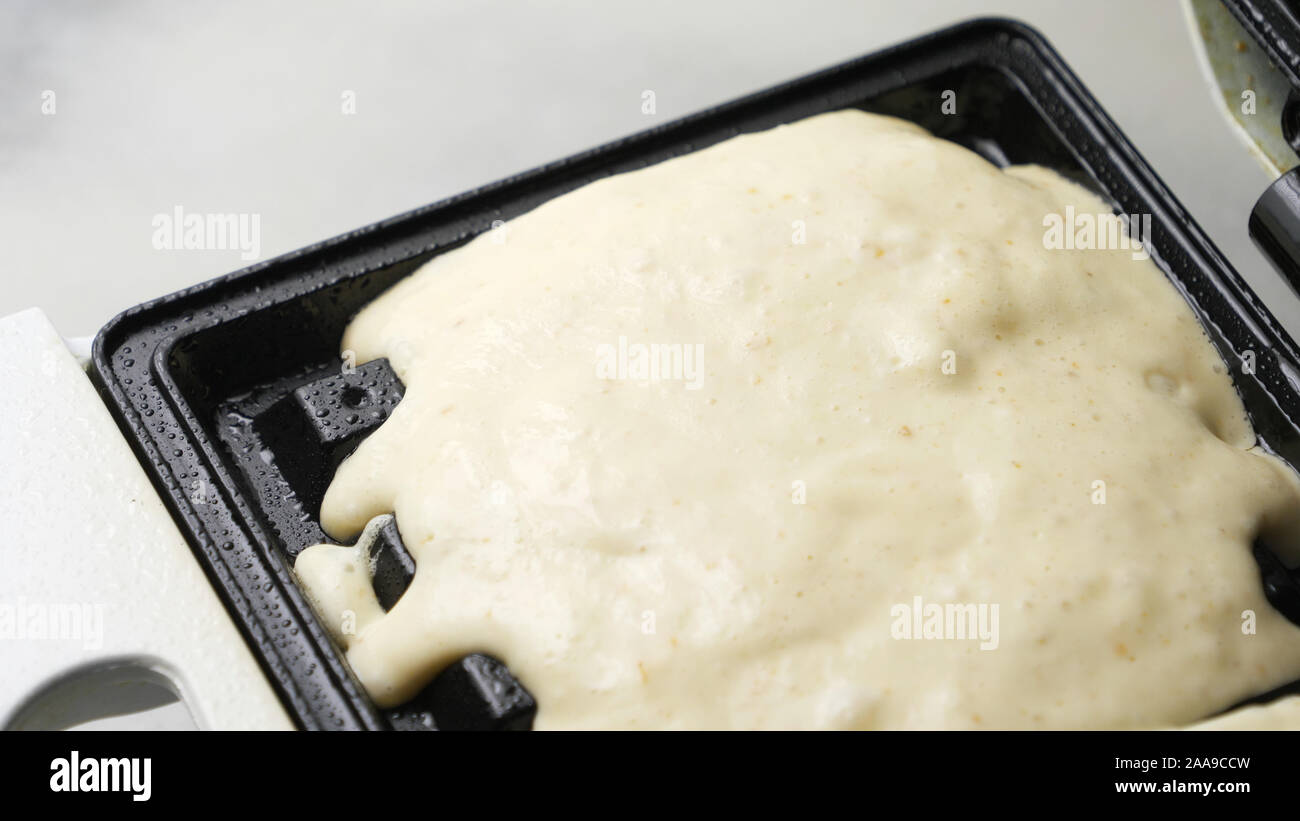 Un waffle fatti.Waffle pastella essendo versata su una piastra per i waffle Foto Stock
