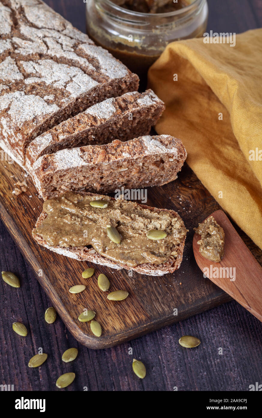 Pane di segale fresco fatto in casa con semi di zucca fatti in casa spalmati su un asse di legno Foto Stock