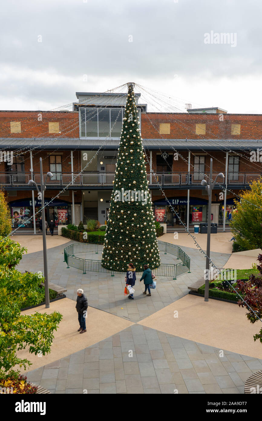 Christmas Shopper camminare davanti a un grande albero di Natale nel centro di Gunwharf Quays a Portsmouth, Hampshire, Regno Unito Foto Stock