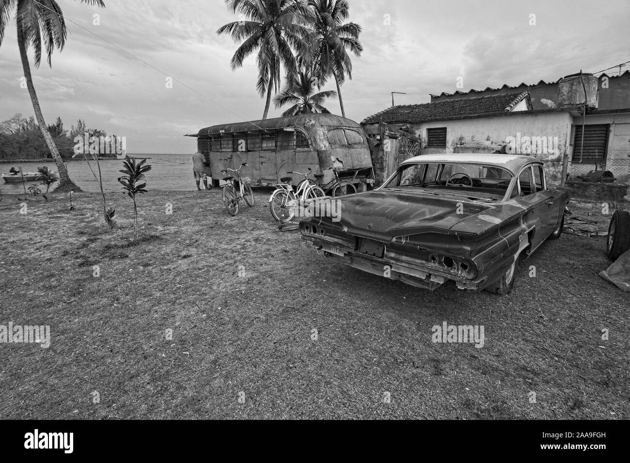 Un appezzamento di terreno accanto a casa con bus urbani degradati, utilizzato come un negozio e la vecchia vettura americana nella piccola cittadina di Caleton sulla costa meridionale di Cuba e dei Caraibi Foto Stock