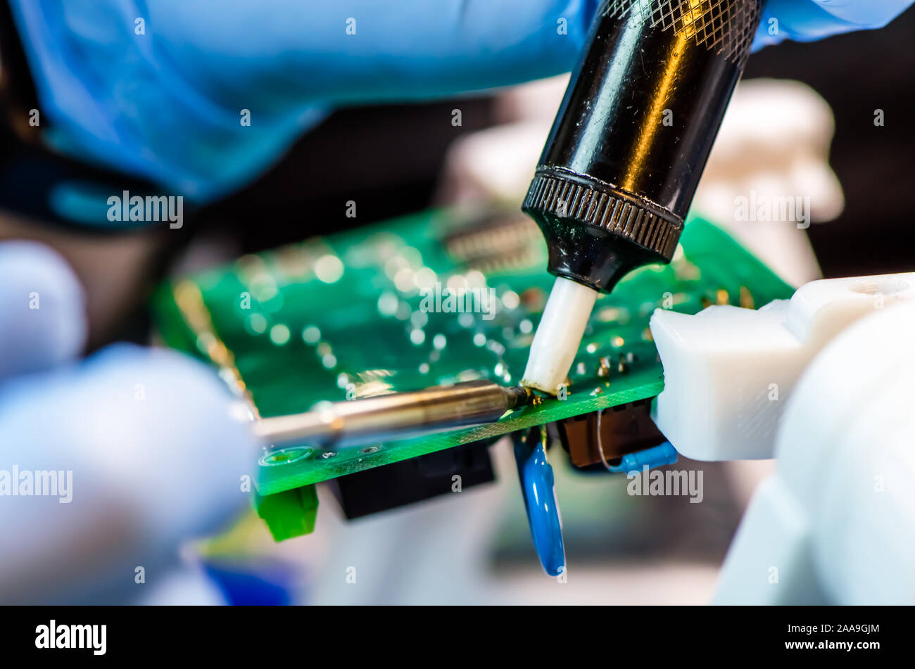 Supporto tecnico lavoratore scende la tassa di PCB. Saldatore. Pinzette a molla Foto Stock