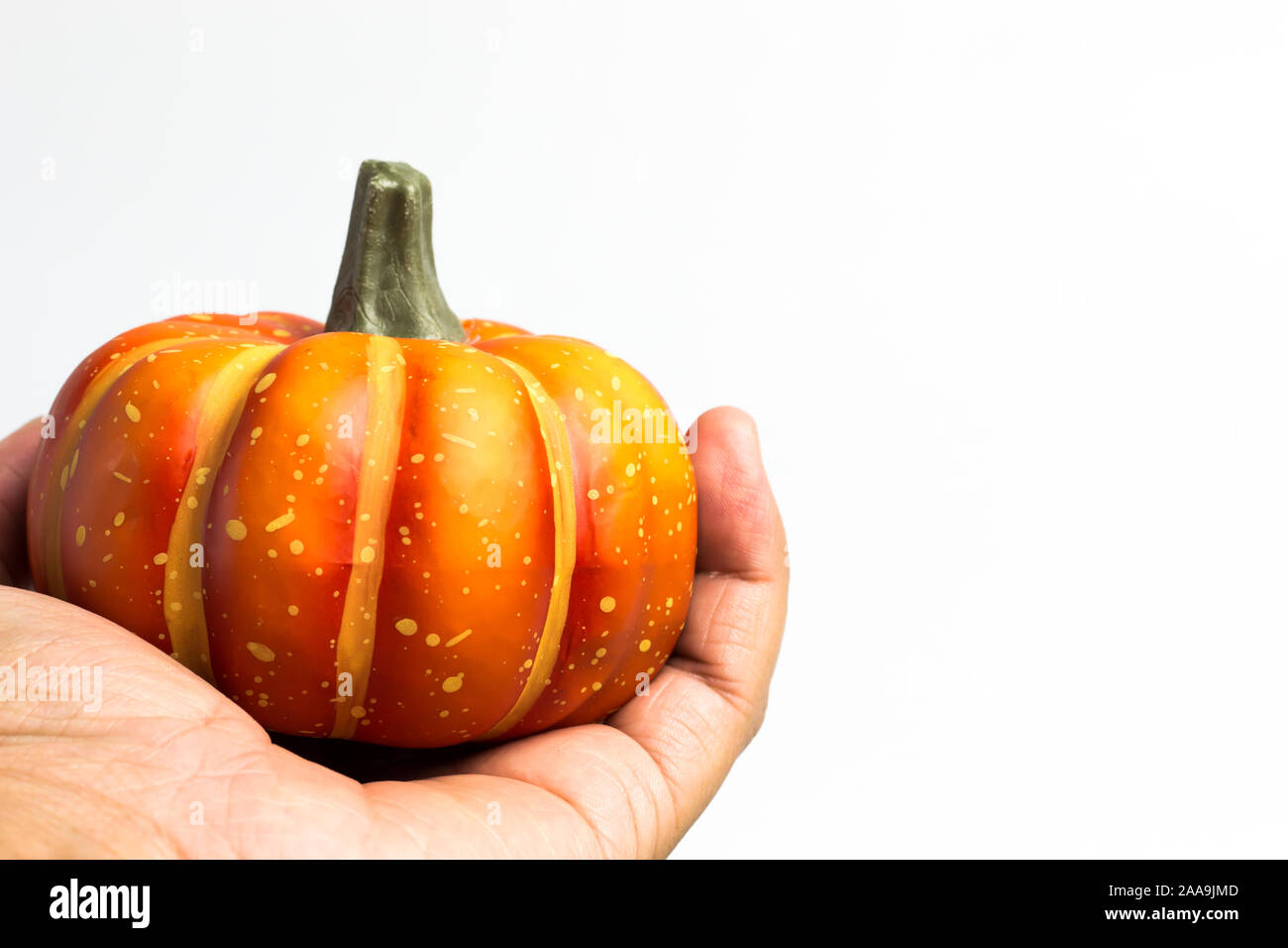 Mano che tiene una zucca per festeggiare Halloween. Arancione zucca in mani sono holding. Foto Stock