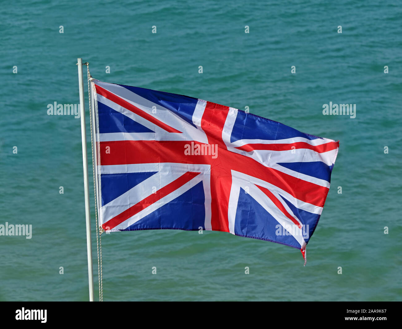 Sventolando Regno Unito bandiera, union jack nella parte anteriore di mare blu Foto Stock