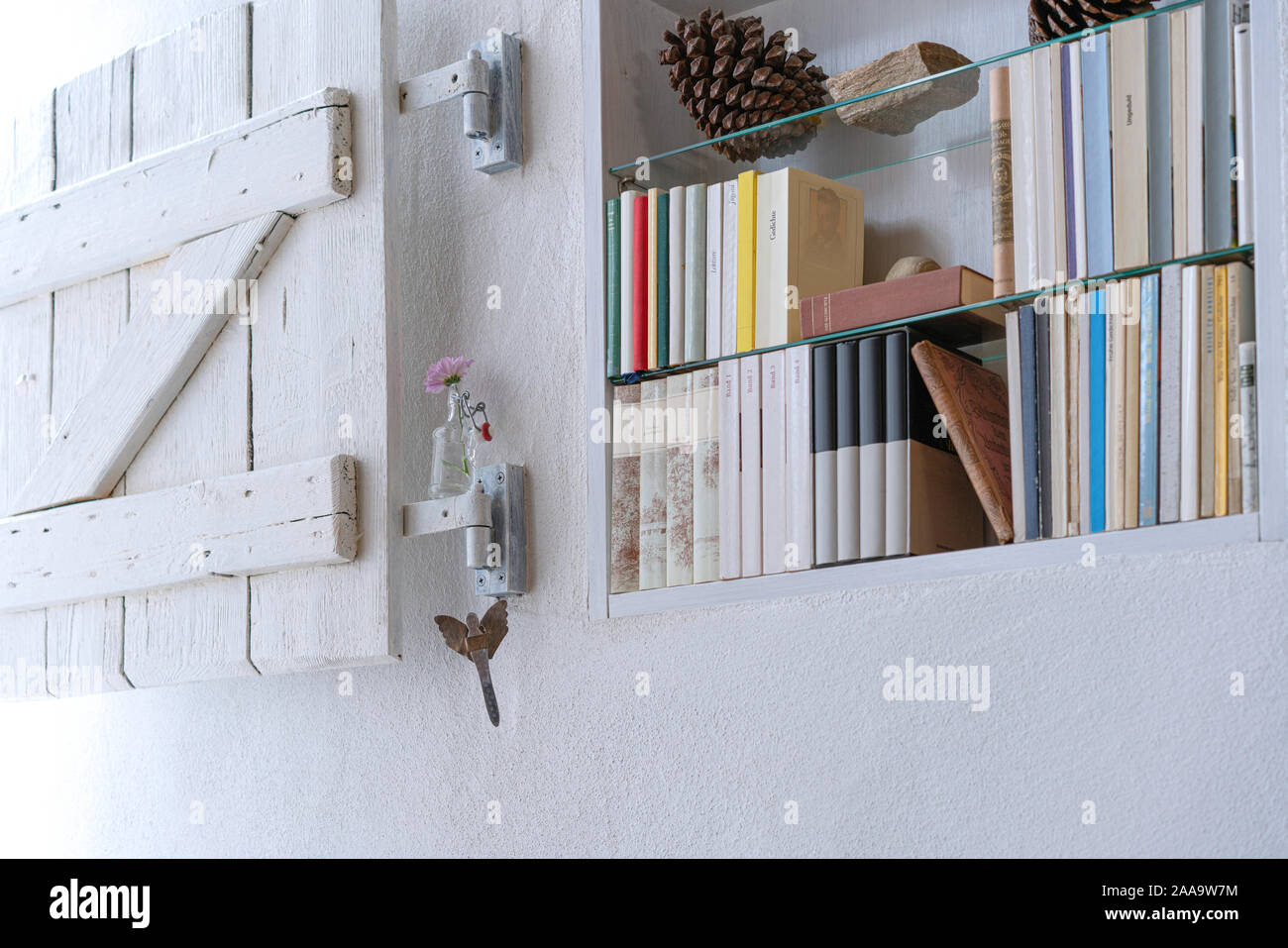 Di piccole dimensioni e decorata con scaffale di legno bianco shabby otturatore in una parete bianca Foto Stock