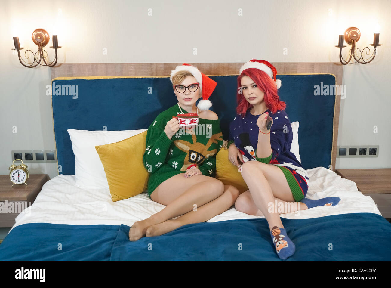 Stile di vita indoor ritratto di due giovane donna in posa di Natale maglioni in camera da letto a Capodanno. Sorridente divertendosi, pronto per la celebrazione. Brigh Foto Stock