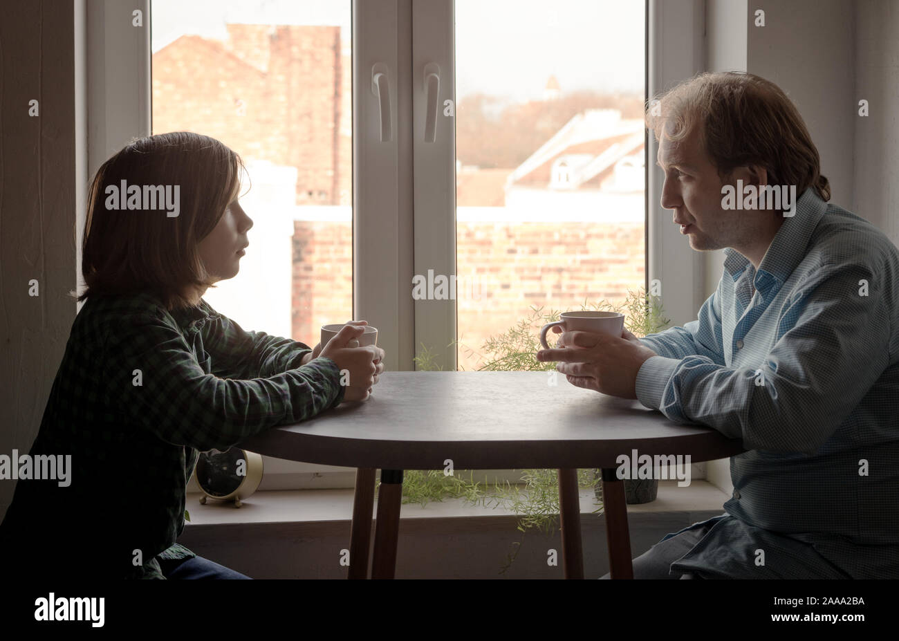 Padre e figlio seduti in cucina al tavolo a bere caffè Foto Stock