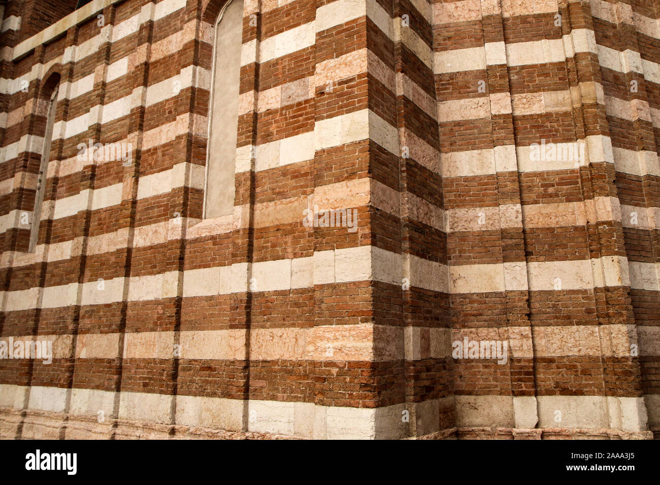 Un dettaglio della facciata dell'italiana Romana Chiesa fatta di mattoni con colori diversi. Il pattern sono le strisce in diverse tonalità. Foto Stock