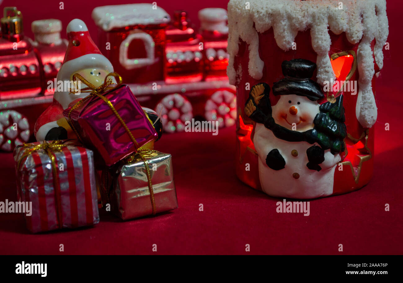 Decorazione ornamenti di Natale. Babbo Natale con regali, treno e pupazzo di neve su sfondo rosso, foto-illustrazione Foto Stock