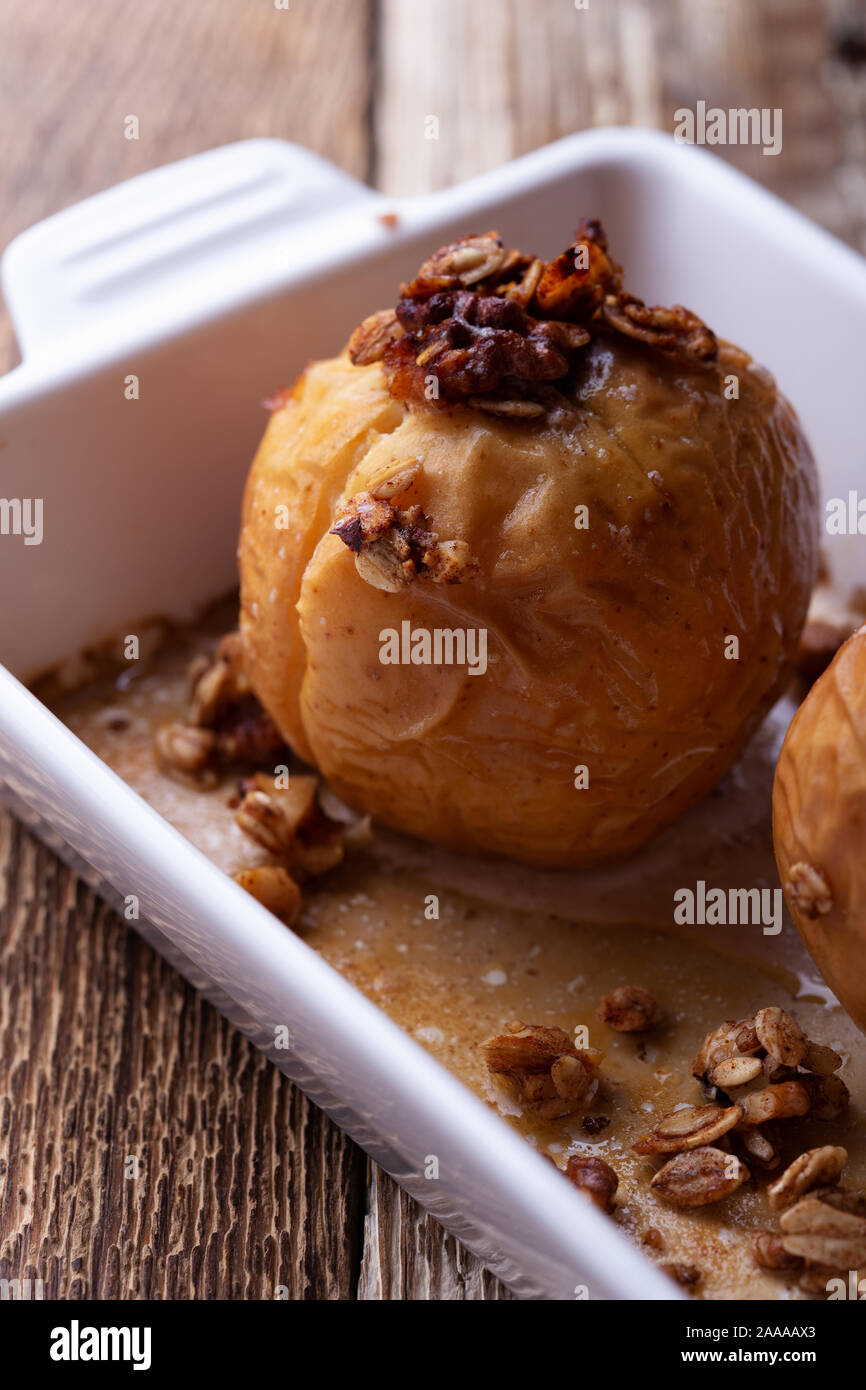Vegan dessert, mele cotte con cereali integrali di avena, noci tritate, sciroppo d'acero sul tavolo di legno, impianto basato in autunno e inverno stagionali pasto vegano, clo Foto Stock